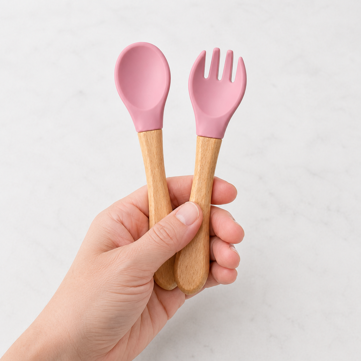 YumBella silicone spoon and fork set held in an adult hand for scale